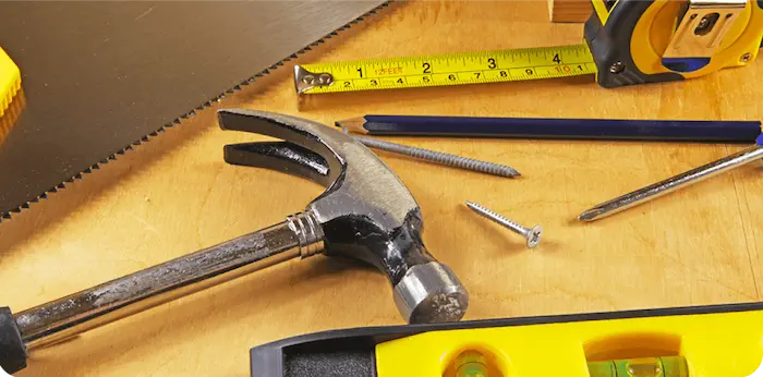 Hand tools, a tape measure, and a level on a workbench