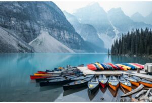 colorful canoes parked on dock with mountain landscape in background
